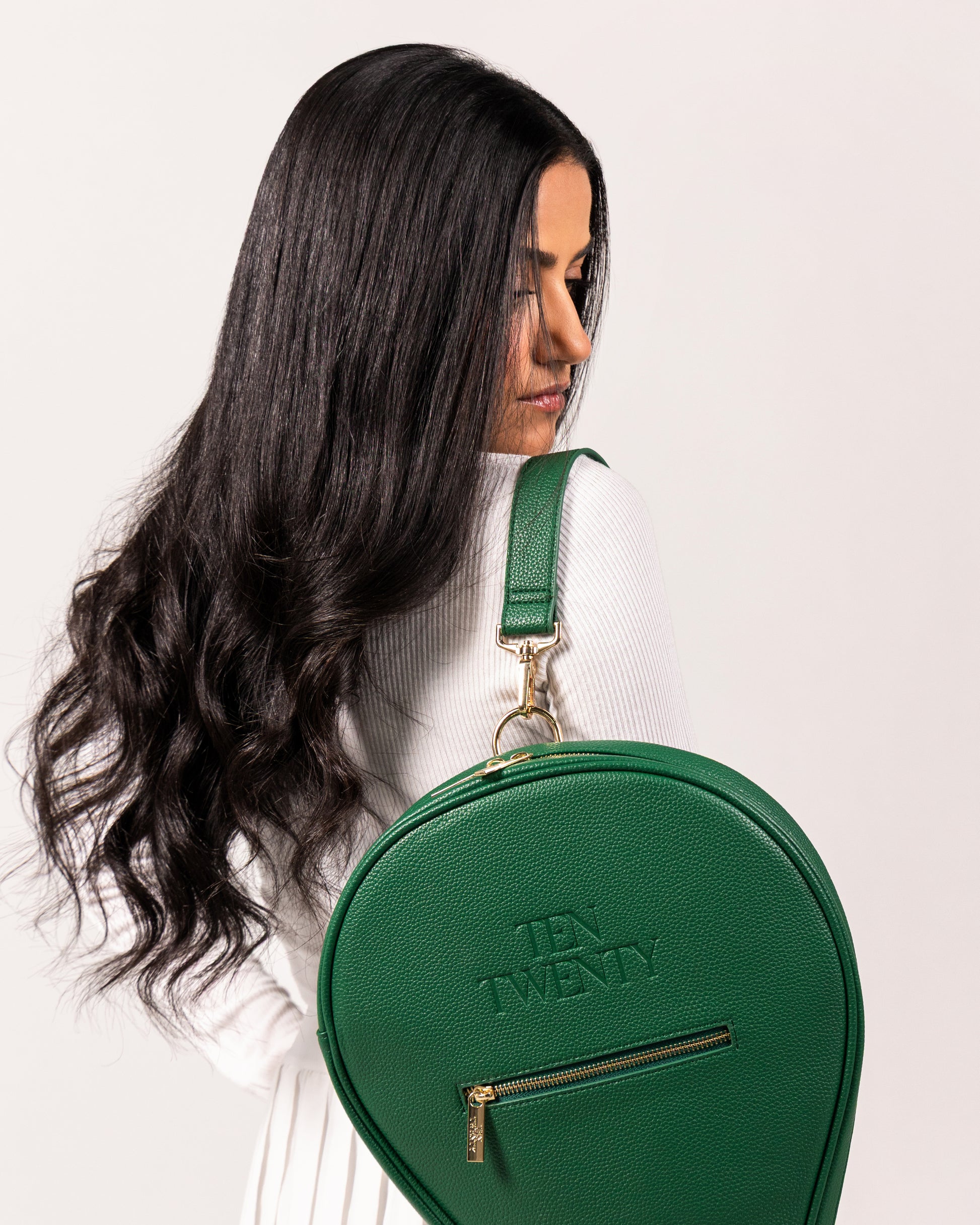 Woman wearing Ten Twenty Emirates Palms premium padel racket bag in forest green vegan leather as shoulder bag - UAE