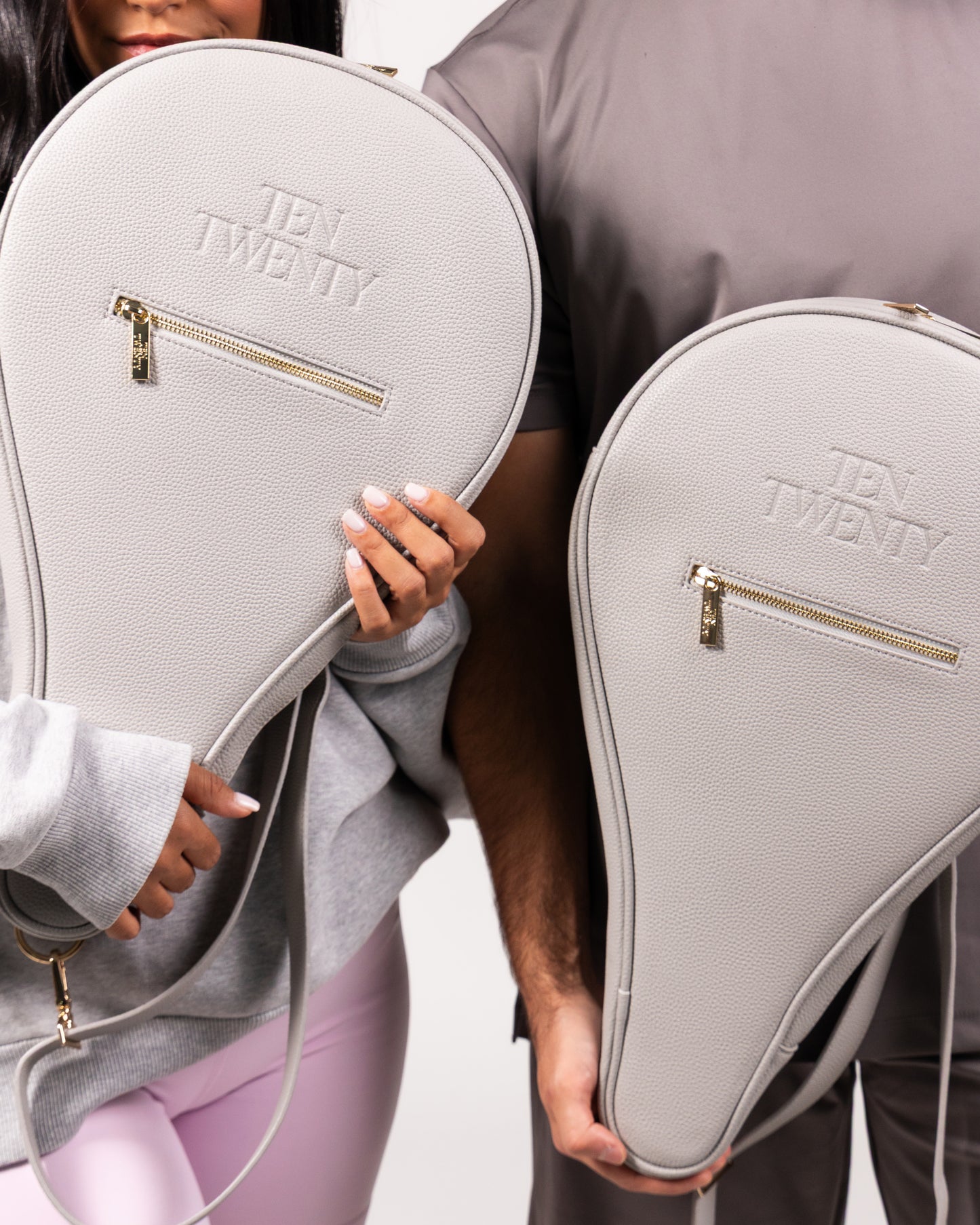 Couple holding Ten Twenty Dubai Skyline premium padel racket bags in light grey vegan leather - Ten Twenty UAE